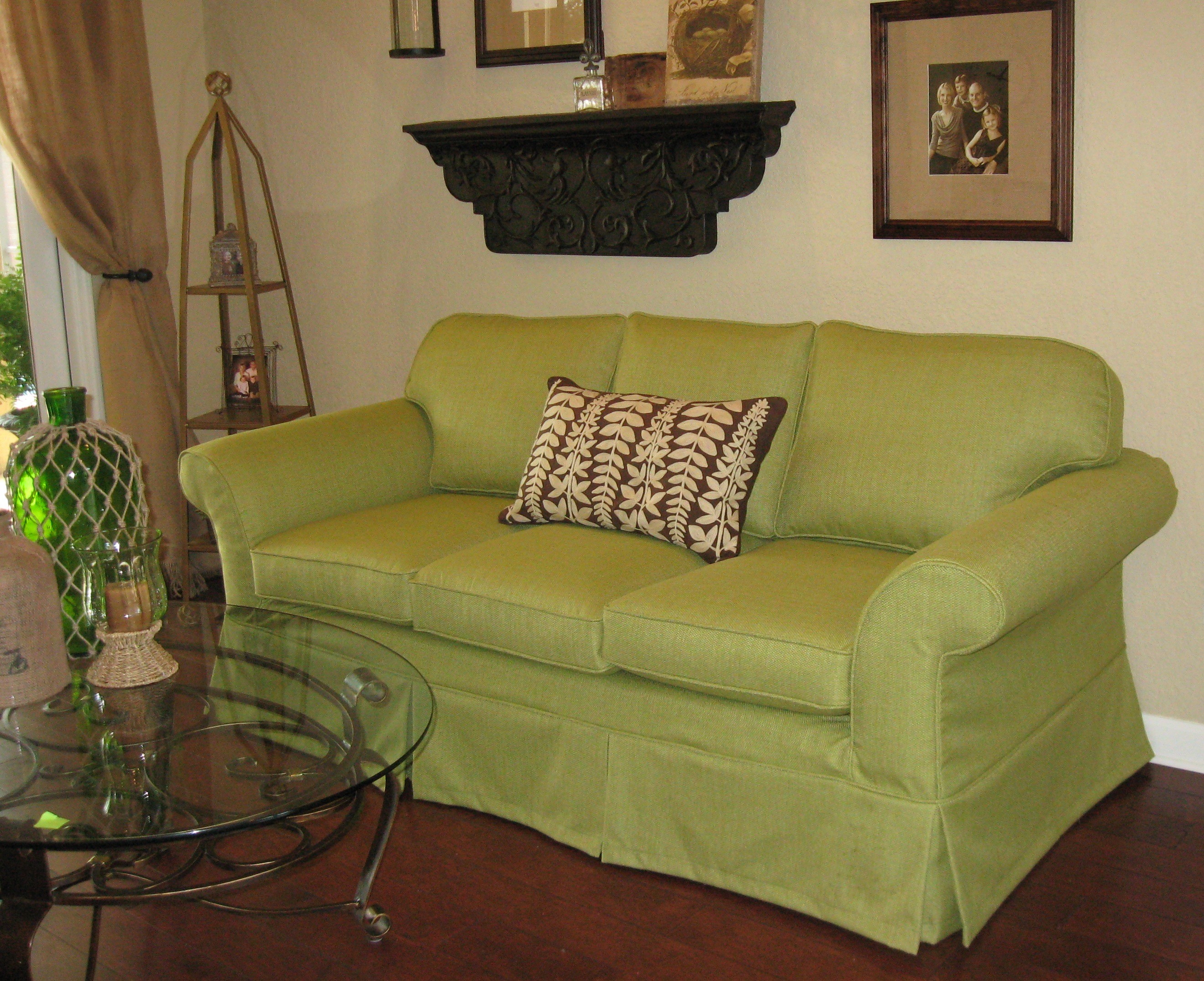 Lime green sofa slipcovered with pleated skirt to the floor in a beige room with brown accents.