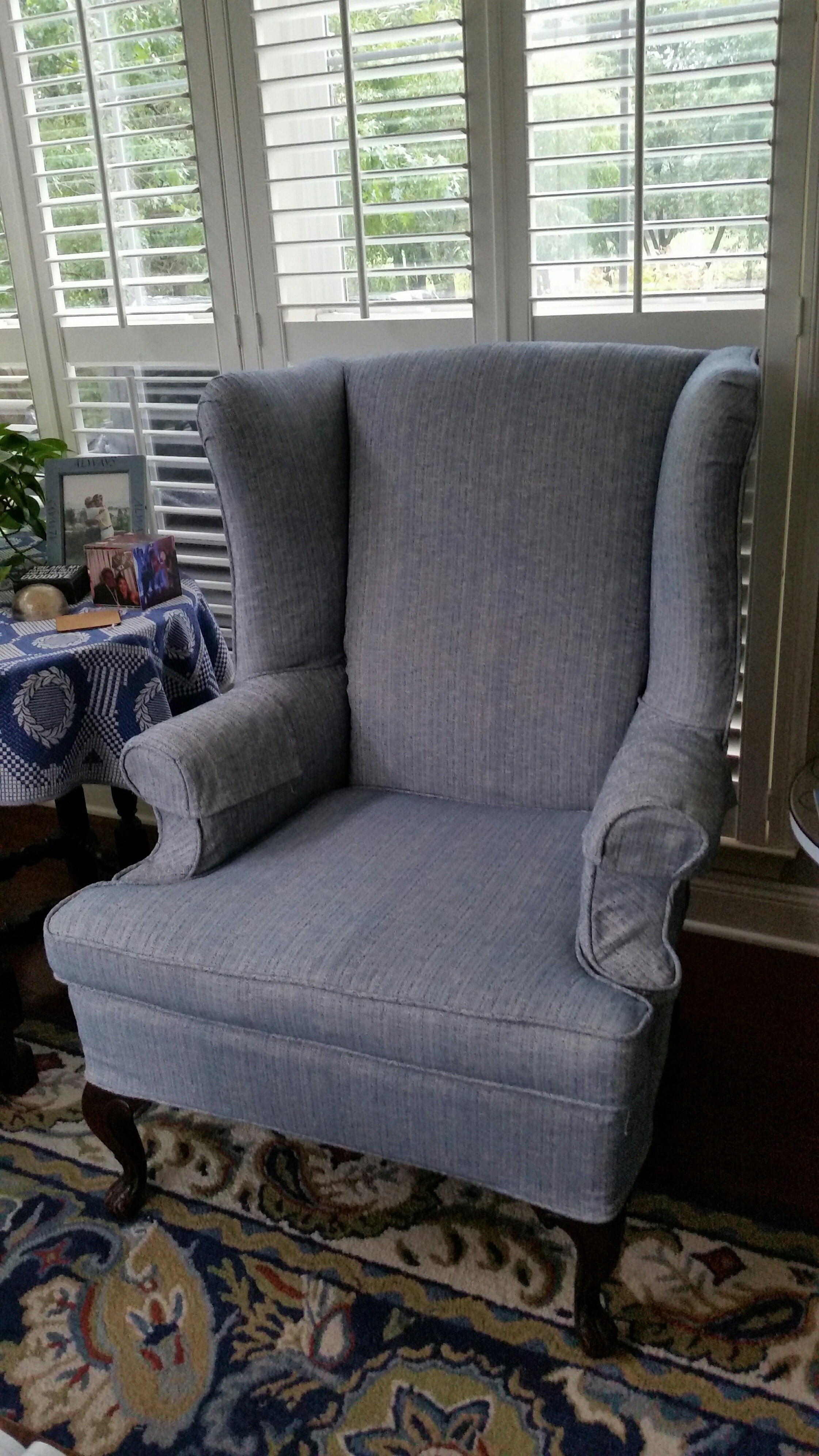 Blue slipcover on queen anne wing chair with wood legs showing.