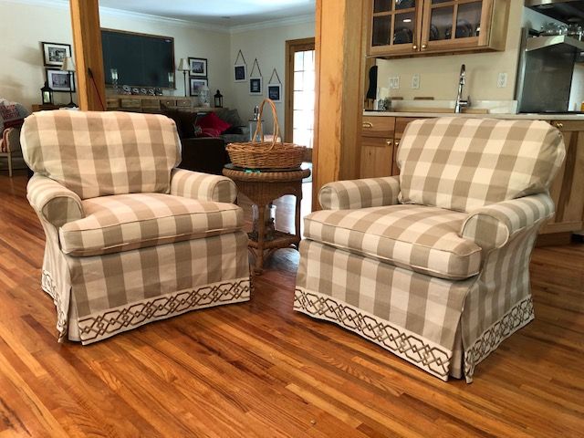 Family room with 2 club chairs slipcovered in beige and white buffalo check fabric with geometric braid trim at bottom of skirt hem